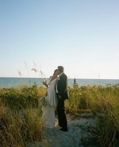 a bride and groom kissing on the beach