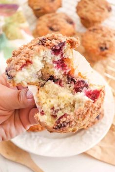 someone is holding up a muffin with cranberry filling