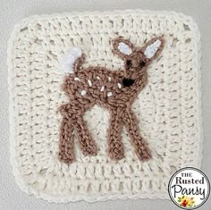 a crocheted deer is on the side of a white square with brown trim