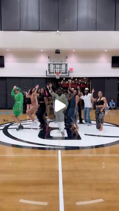 a group of people standing on top of a basketball court with their arms in the air