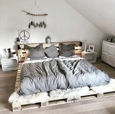 a bed made out of wooden pallets in a room with white walls and wood flooring