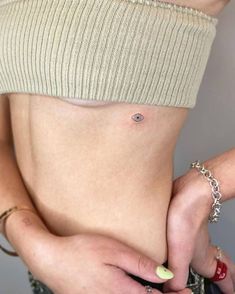 a woman with tattoos on her stomach holding onto the side of her body and wearing bracelets