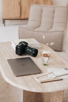 a wooden table topped with a laptop computer next to a camera and other items on top of it