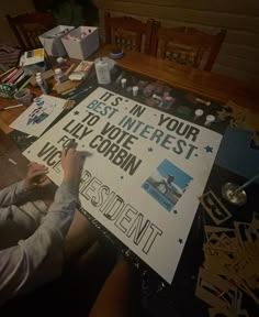 a person sitting at a table writing on a sign