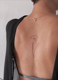 the back of a woman's neck with a flower tattoo on her left shoulder