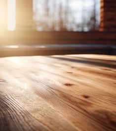 an empty wooden table with sunlight coming in through the window and wood flooring behind it