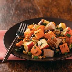 a black plate topped with tofu and veggies next to a pink napkin