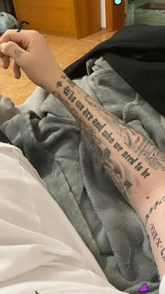 a person laying in bed with tattoos on their arm and leg, holding a cell phone