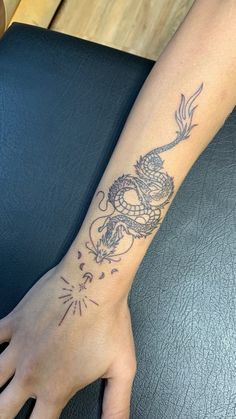 a woman's arm with a dragon tattoo on the left side of her hand