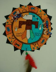 a paper plate with a cross on it and a red feather hanging from the side