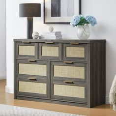 a gray and beige dresser with drawers in a living room next to a painting on the wall