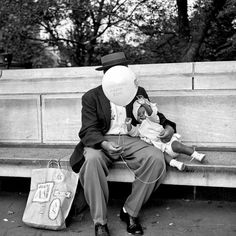 a man sitting on a bench with a baby in his lap and a balloon attached to his head