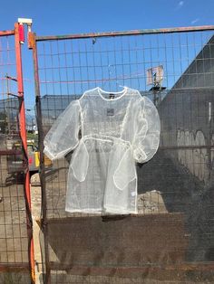 a white shirt is hanging on a fence