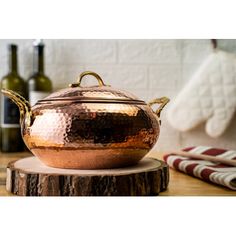 a large copper pot sitting on top of a wooden table