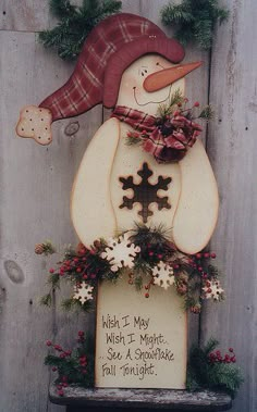 a snowman decoration on the side of a wooden fence with words written below it