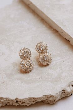 two pairs of earrings sitting on top of a stone slab