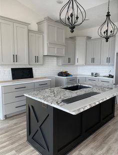 an image of a kitchen with white cabinets and granite counter tops in the center island