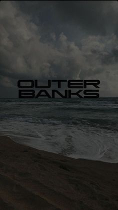 the words outer banks are written in black on a dark cloudy day at the beach