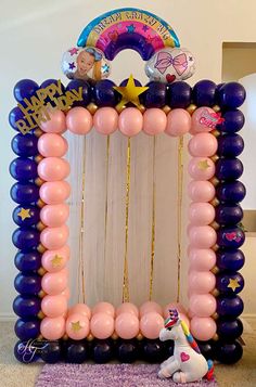 a unicorn balloon arch with balloons on the top and an animal toy sitting in front of it