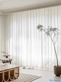 a living room filled with furniture and a large window covered in white drapes