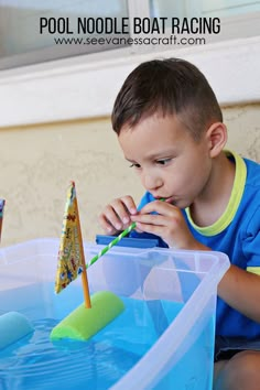 a young boy sitting in front of a blue container filled with water and an umbrella