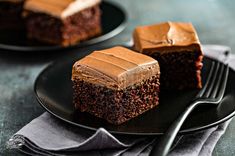 two slices of chocolate cake on black plates