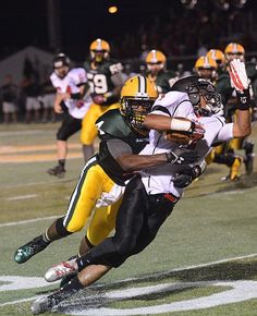 a football player running with the ball in his hand and another person on the ground behind him