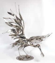 a metal sculpture of a bird on a white background