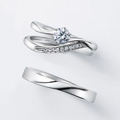 two white gold wedding rings with diamonds on each one and an engagement ring in the middle