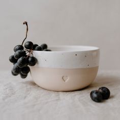 a white bowl filled with black grapes on top of a table