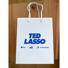 a white shopping bag hanging from a wooden wall with the words ted lasso on it