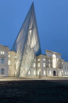 a large white building with a very tall triangular shaped structure in front of it at night