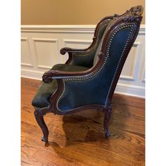 an antique chair with blue upholstered fabric and wood trimmings on the back