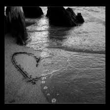 a heart drawn in the sand at the beach with waves coming in from the ocean