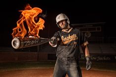 a man holding a baseball bat on top of a field with fire in the air