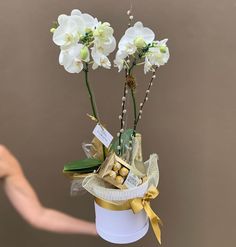 a white hat with flowers and chocolates in it is held up by a hand