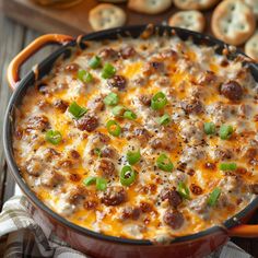 a casserole dish with sausage, cheese and green peppers in it on a wooden table