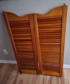 a pair of wooden shutters sitting on top of a hard wood floor next to a wall