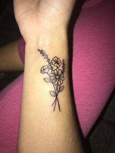 a woman's wrist tattoo with flowers on the left side of her right arm