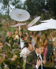 a group of people standing around each other with umbrellas in the air above them