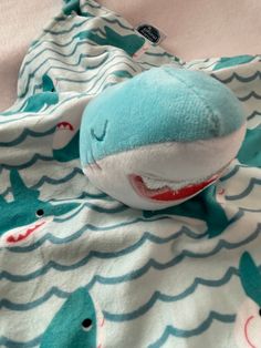 a stuffed shark laying on top of a blanket