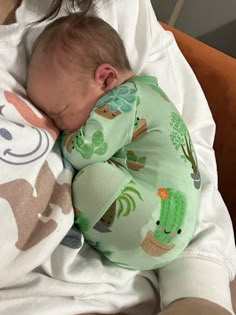 a baby sleeping on top of a blanket next to a stuffed animal toy in a woman's lap