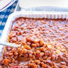 baked beans being spooned into a casserole dish