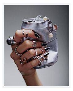 a woman's hand holding a metal can with rings on it and an open lid