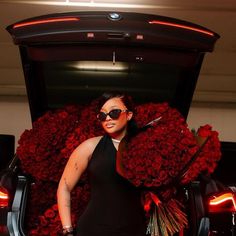 a woman standing in front of a car covered in roses