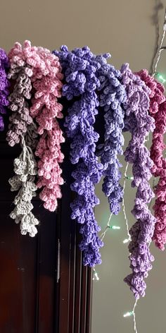 several crocheted flowers are hanging from the side of a door with lights in the background