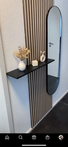 a black shelf with two white vases on it and a mirror hanging from the wall