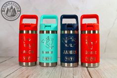 three different colored stainless steel water bottles sitting next to each other on a wooden table