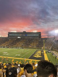 a football stadium filled with lots of people watching the sun go down in the sky