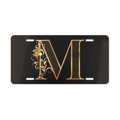 a black license plate with the letter m in gold floral design on it's front